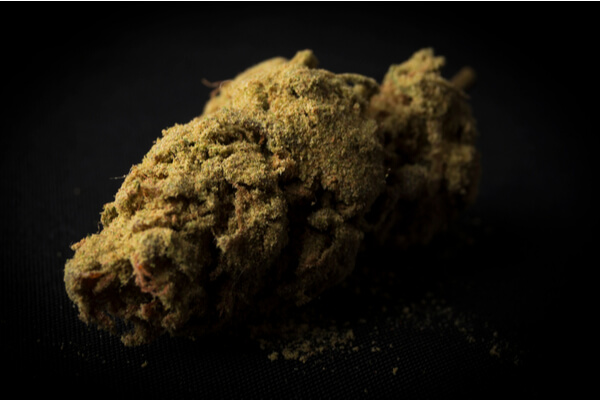 A moonrock marijuana bud mixed with bho and kief on a black background