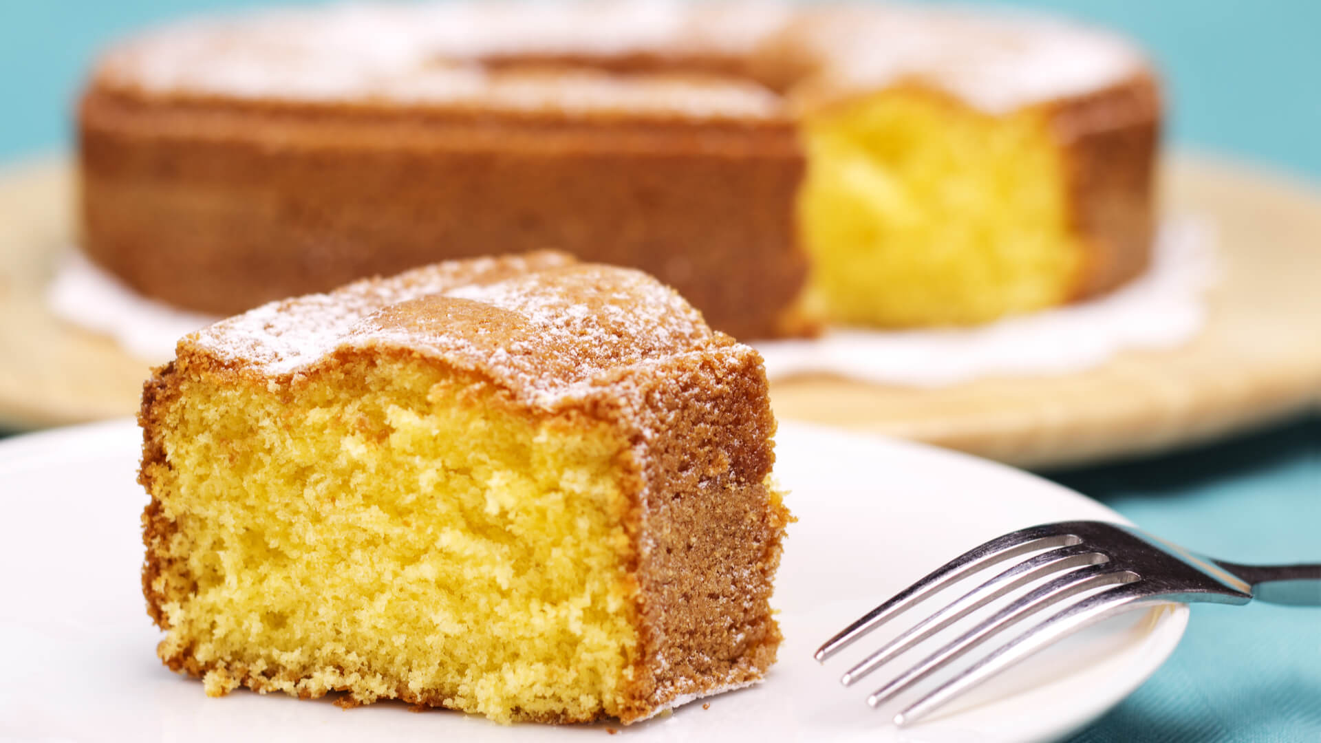 A closeup of a piece of lemon cake with icing sugar