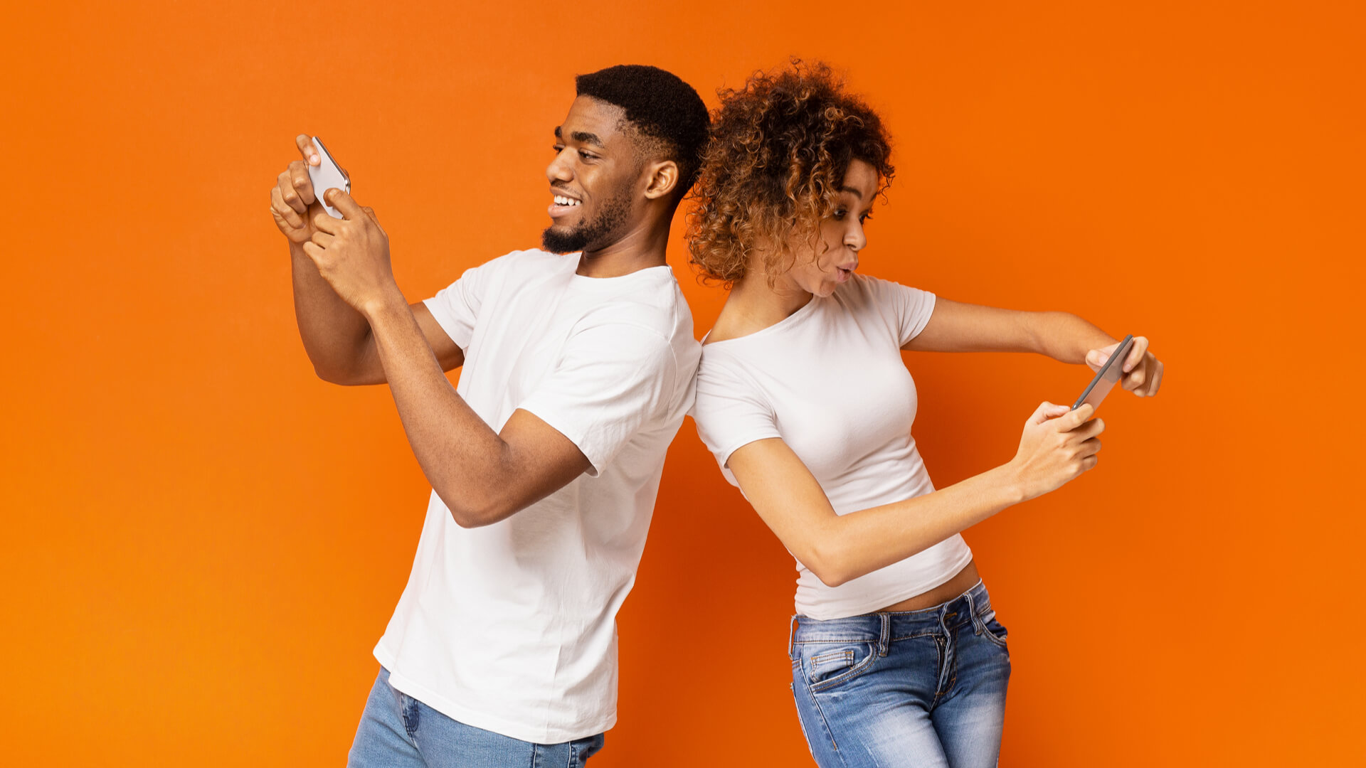 a man and women playing a video game on cellphones on a orange background