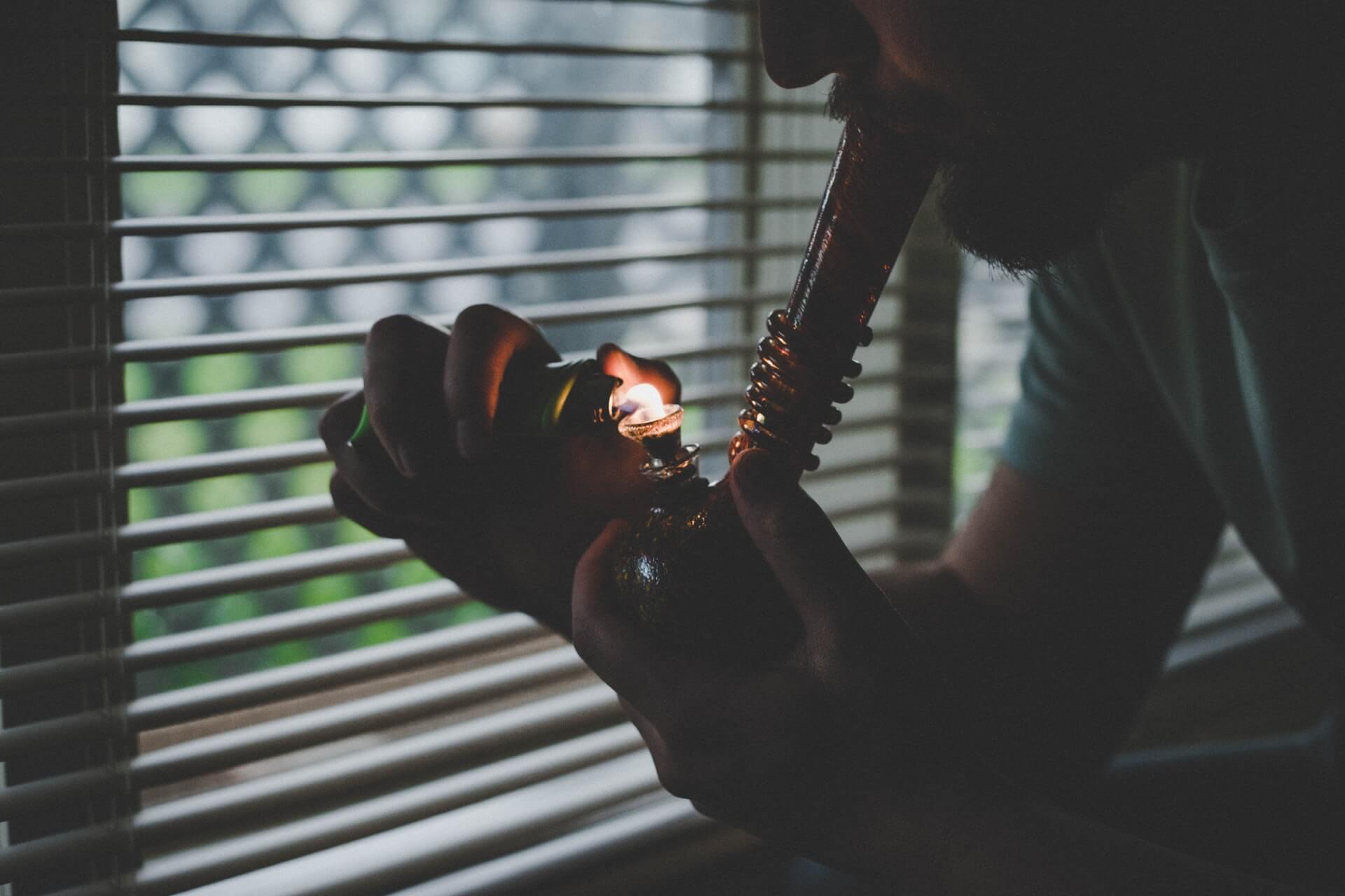 a man lighting a bowl while smoking a bong